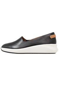 Chaussure noire en cuir au design élégant, à coupe basse, avec une semelle en wedge blanche. Présente un petit détail de sangle beige au niveau du talon.