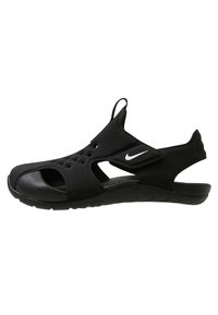 Chanclas deportivas negras fabricadas con un material de goma flexible, diseño de punta abierta y múltiples agujeros de ventilación. Presentan un logo lateral y una correa ajustable.