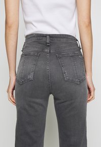 Gray denim jeans with a high waist, two back pockets, and a slightly faded texture. The fabric appears soft with a straight-leg cut.