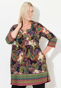Zwarte en meerkleurige tuniek met paisleypatroon, met driekwart mouwen, vierkante halslijn en verzamelde taille, met levendige accenten.