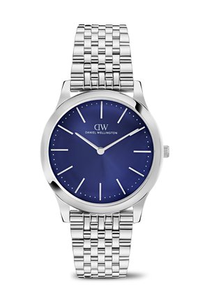 Reloj de pulsera de metal plateado con esfera azul, marcadores de hora blancos mínimos y agujas finas que muestran las 10:10, de la marca Daniel Wellington.