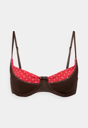 Bruine beha met een gladde textuur, voorzien van een rood bloemenpatroon aan de binnenvoering en een klein bruin strikje in het midden. Inclusief verstelbare bandjes.