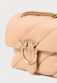 Bolsa de mão em pele pêssego com design acolchoado, apresentando um detalhe em metal dourado com dois pássaros a beijar. Alça em corrente anexada.