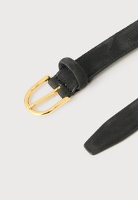 Cinturón de ante negro con textura suave y hebilla de metal dorado pulido sobre un fondo claro.