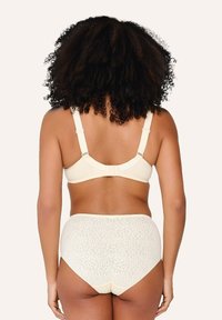 Beige bh met verstelbare bandjes en een haaksluiting, gecombineerd met hooggetailleerde slipjes met een bloemenpatroon in een lichtere beige tint.