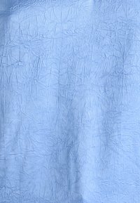 Světle modrá zmačkaná tkanina s texturovaným povrchem, která má různá pomačkaní a vzory. Měkký, mírně odrazový vzhled.