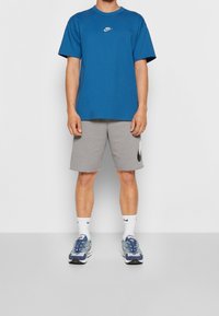 Nike blå bomulls T-shirt med korta ärmar och en vit logotyp, tillsammans med grå shorts med en svart logotyp. Färgglada träningsskor.