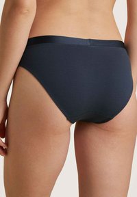 Donkerblauwe katoenen slipjes met een gladde textuur, een middelhoge snit en een satijnen taillebanddetail. Heeft naadloze randen voor extra comfort.