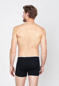 Zwarte boxershorts met een grijze tailleband, met een gladde textuur en een aangesloten ontwerp, gezien vanuit de achterkant.