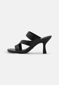 Las sandalias negras de tacón presentan un diseño elegante con dos amplias correas entrecruzadas y un tacón alto y esbelto, elaboradas con un material suave de acabado mate.