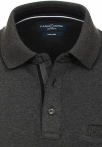Mørkegrå polo t-shirt med struktureret stof, ribbet krave, tre-knaps knaplukning og en lille lomme på venstre side.