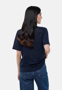 T-shirt bleu marine à manches courtes avec une coupe décontractée. Tissu doux et léger avec une texture subtile, associé à un jean bleu taille haute.