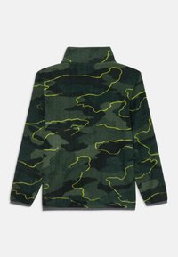 Zöld kamuflázs mintás fleece dzseki sárga részletekkel. Magas nyakú, hosszú ujjú, sima tapintású. Az alján kontrasztos szürke szegély található.