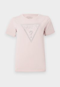 Camiseta de color rosa claro, hecha de algodón y con mangas cortas. Presenta un gráfico triangular con la palabra "GUESS" y piedras brillantes decorativas.