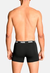 Schwarze Boxer-Briefs aus weichem Stoff mit einem kontrastierenden weißen Puma-Logo am Bund. Das Design ist eng anliegend und minimalistisch.