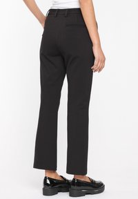 Black, straight-leg pants with a smooth fabric finish. Features a single back pocket and belt loops. Paired with shiny black loafers.
