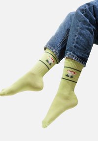 Jasnozielone skarpetki w prążki z małym wzorem przedstawiającym kwiat oraz liście w kolorze czerwonym i zielonym, wykonane z miękkiego, elastycznego materiału.