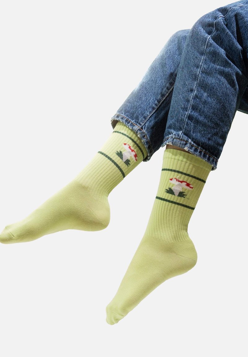 Jasnozielone skarpetki w prążki z małym wzorem przedstawiającym kwiat oraz liście w kolorze czerwonym i zielonym, wykonane z miękkiego, elastycznego materiału.