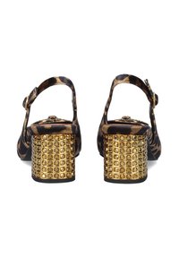 Zapatos slingback de estampado de leopardo con un grueso tacón dorado con clavos. Parte superior de tejido suave, correa ajustable y acentos dorados texturizados.