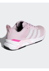 Rožnata športna obutev z zgornjim delom iz mrežastega in sintetičnega materiala, belim trirazsežnim vzorcem, teksturiranim prstnim delom ter rožnatimi poudarki na peti in srednjem podplatu.