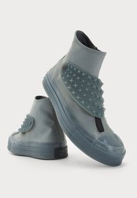 Botins cinzentos até ao tornozelo feitos de borracha com um acabamento texturizado em padrão de estrelas e fecho de zipper. Apresentam um bico arredondado e sola em camadas.