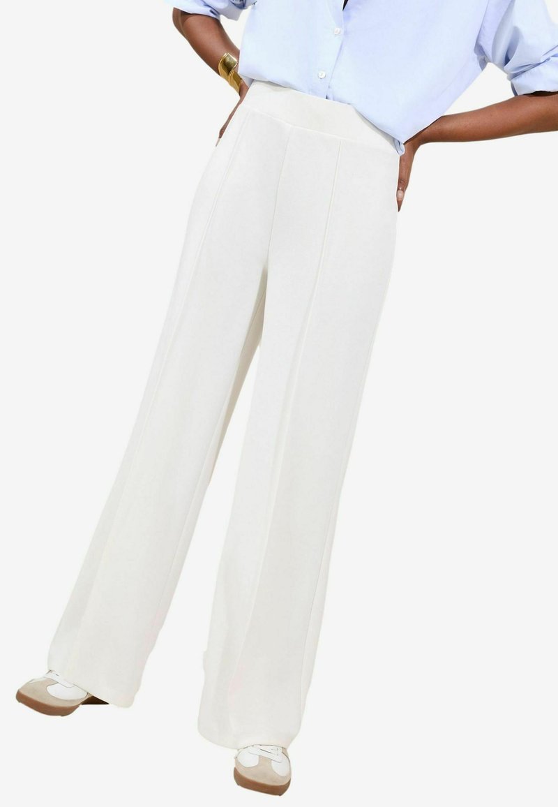 Witte wijde broek met hoge taille, met strakke lijnen en een gladde textuur. Gecombineerd met lichte sneakers.