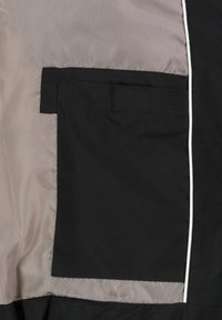 Zwarte jas binnenkant met een grijze voering, voorzien van een vierkant zwart zakje en witte biezen langs de rand. Gladde textuur en duurzaam materiaal.