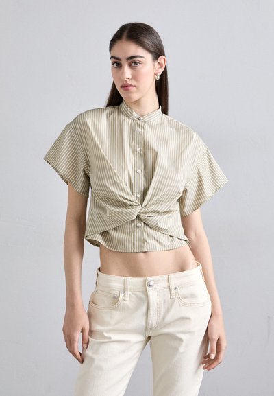 Chemise à manches courtes, cropped, en beige clair avec des rayures blanches verticales, dotée d'une fermeture à boutons devant et d'un détail noué à la taille.