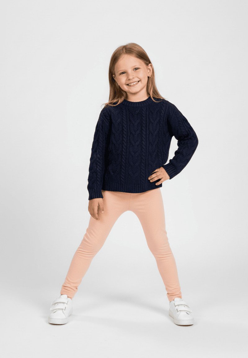 Granatowy sweter z dzianiny warkoczowej zestawiony z jasnoróżowymi legginsami i białymi trampkami. Strój charakteryzuje się luźnym krojem i teksturowanymi wzorami.