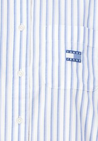 Striped button-up shirt in blue and white cotton, featuring a left chest pocket with a blue and white "TOMMY JEANS" label.