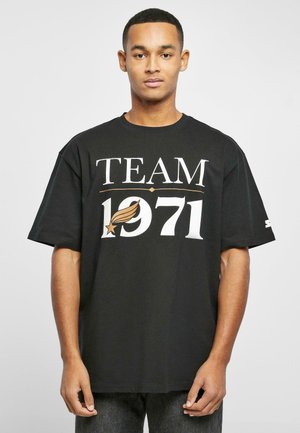Black cotton t-shirt featuring bold white text "TEAM 1971" with a stylized emblem. Loose fit with short sleeves and a round neckline.
