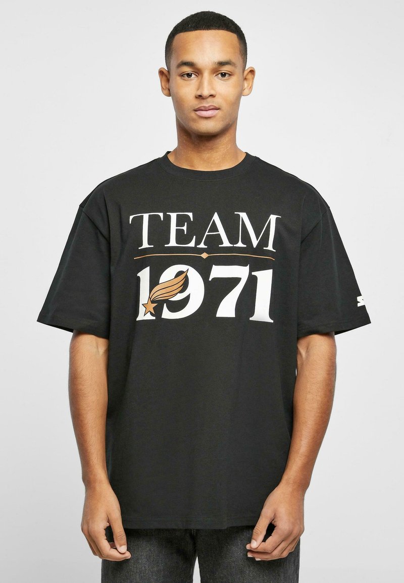 Tricou din bumbac negru cu text alb îndrăznic "ECHIPA 1971" și un emblema stilizată. Croiala lejeră, cu mâneci scurte și guler rotund.