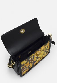 Czarna skórzana torebka z logo w kolorze złotym oraz ozdobnym wzorem w żółto-czarne na przodzie. Wnętrze zawiera kieszeń na zamek.