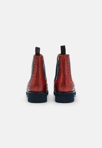 Bottes en cuir à la cheville avec un dos en croco rouge embossé, un devant lisse bleu marine, une semelle ribbed bleue et des panneaux latéraux élastiques pour un enfilage facile.