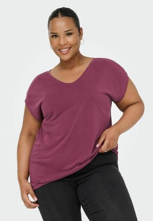 Korte mouwen, v-hals top in een effen bordeauxrode kleur, met een ontspannen pasvorm en een gladde textuur, gecombineerd met donkere spijkerbroeken.