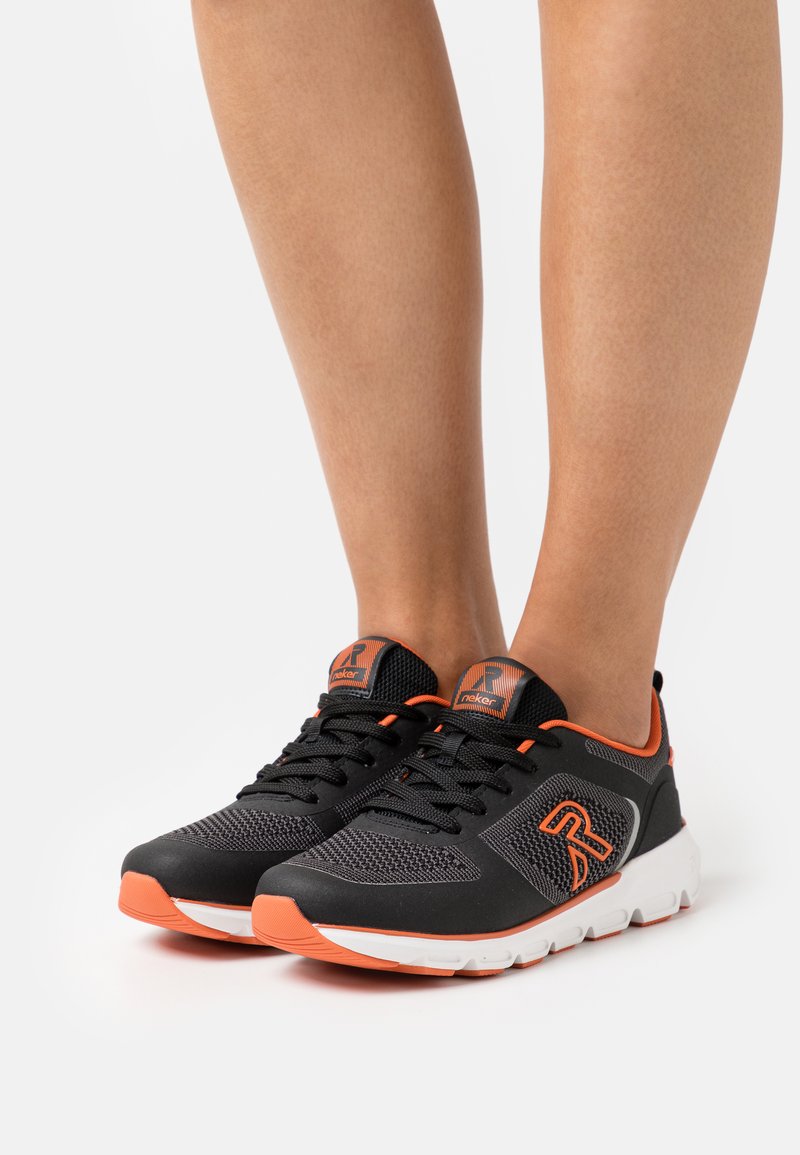 Czarne buty sportowe z pomarańczowymi akcentami; siateczkowa cholewka, gumowa podeszwa i wyściełany kołnierz. Posiada sznurowadła i logo na boku.
