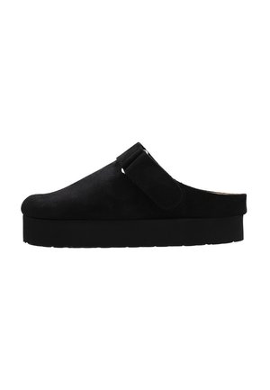 Zapato negro sin cordones con gruesa suela plataforma y correa ajustable en la parte superior, hecho de material similar a la gamuza.