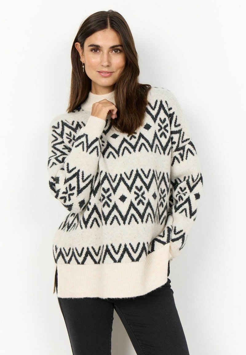 Cream sweater with black geometric patterns, long sleeves, high neckline, side slits, and a relaxed fit. Soft texture, knit material.
