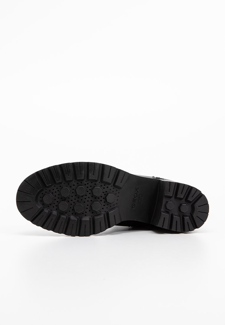 Semelle de chaussure en caoutchouc noir avec une texture antidérapante, présentant des motifs hexagonaux et circulaires pour une meilleure adhérence. Marquée du nom de la marque "Geox."