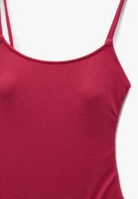 Maillot de bain une pièce rouge texturé avec des fines bretelles et un décolleté en scoop, présentant un motif côtelé et une finition lisse.