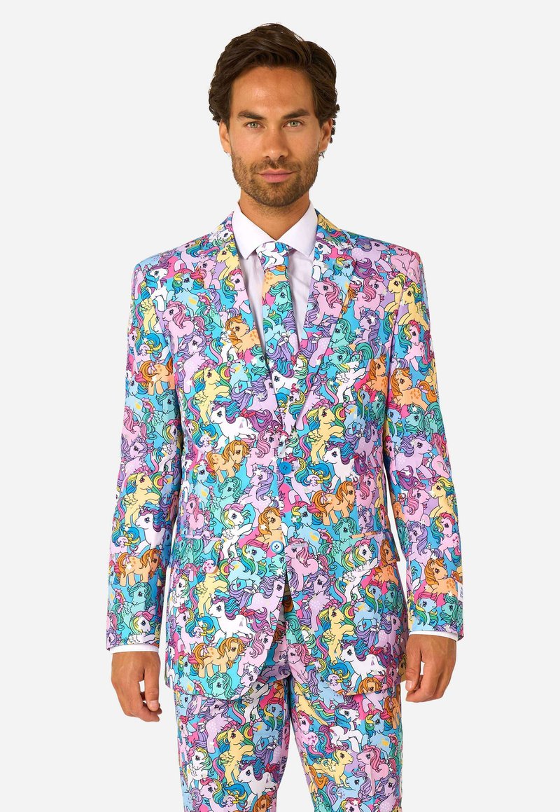Uomo che indossa un completo colorato con un motivo di vari pony dei cartoni animati in colori pastello, con cravatta abbinata e camicia bianca.