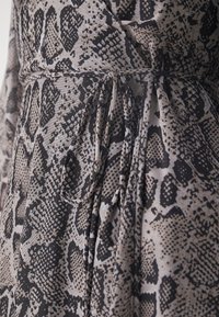 Tissu imprimé serpent marron et beige avec une surface texturée, incluant des fronces et un détail de lien à la taille.