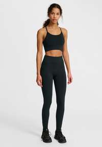 Zwarte sportcrop top met bijpassende hoge taille leggings, gemaakt van rekbare stof. Voorzien van dunne bandjes en een naadloos ontwerp.