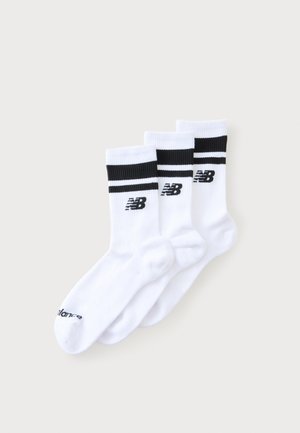 Drei weiße Crew-Socken mit schwarzen Streifen und dem New Balance-Logo nahe der Oberseite, überlappend auf einem einfarbigen Hintergrund angeordnet.