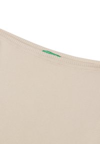 Beige bomulls t-shirt med ribbad halsringning och en grön etikett som står "United Colors" nära kragen. Sl ät textur och enkel design.