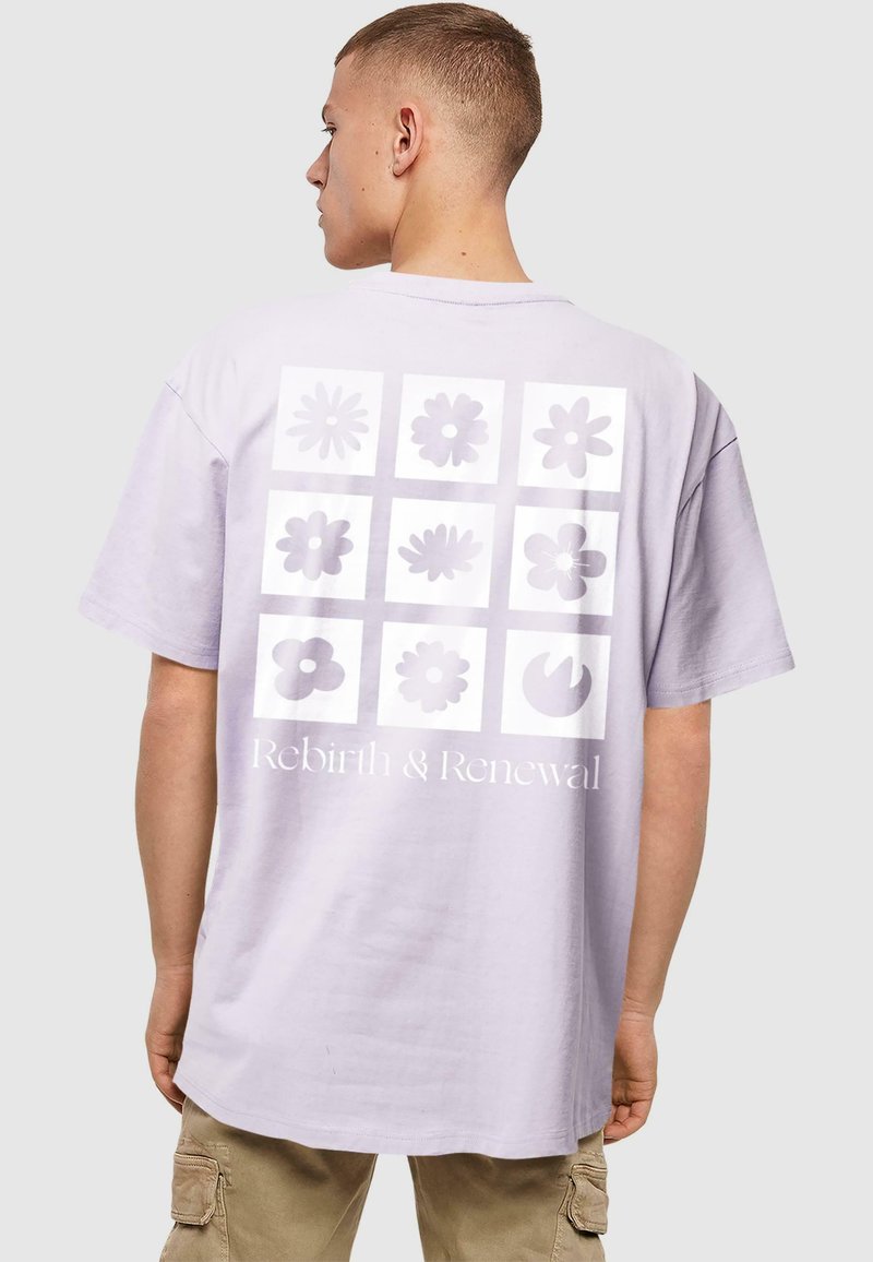 Lilla bomulds t-shirt med et stort, gitterlignende blomstermotiv i forskellige nuancer af lilla med teksten "Genfødsel & Fornyelse" nedenfor.
