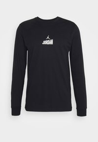 Musta pitkähihaine t-paita, joka on valmistettu puuvillasta. Paita sisältää pyöreän kaula-aukon, ribbatut hihansuut ja rinnassa on valkoinen "JORDAN"-logo.