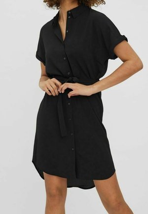 Sorte knap-up kjole med korte ærmer, en belagt talje og en let buet kant. Fremstillet af glat materiale, har den en klassisk krave.