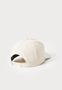 Casquette de baseball beige avec un devant rigide, une visière courbée et une sangle en plastique ajustable. Texture de tissu lisse avec des coutures renforcées.
