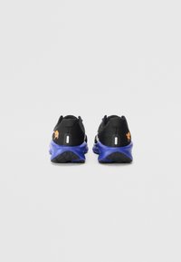 Scarpe sportive nere con finitura testurizzata, suole viola e accenti arancioni del logo. Presentano dettagli riflettenti e un design imbottito.
